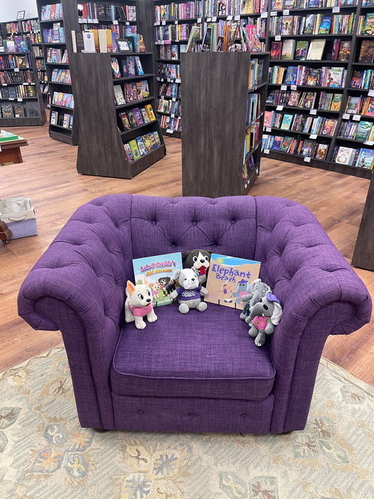 Christine Devane's books and character stuffies displayed on a purple tufted chair at The Purple Couch bookstore in North Andover